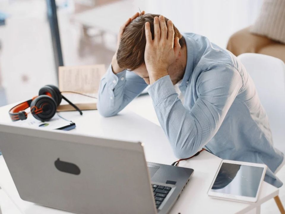 Lavoratore al computer affaticato dal technostress e dai rischi della sicurezza sul lavoro digitale